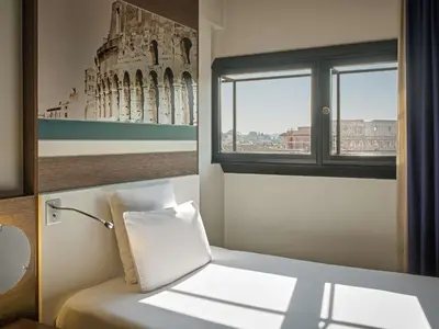 a hotel room with a bed and a suitcase at Mercure Roma Centro Colosseo in Rome