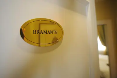 a round gold sign on a wall with the words braaminate at Residenza Paolo VI in Rome
