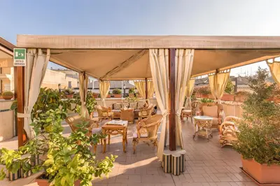 a covered patio with chairs and tables and plants at Hotel Impero in Rome