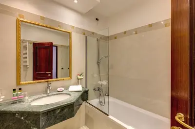 a bathroom with a tub and a sink and a mirror at Hotel Impero in Rome