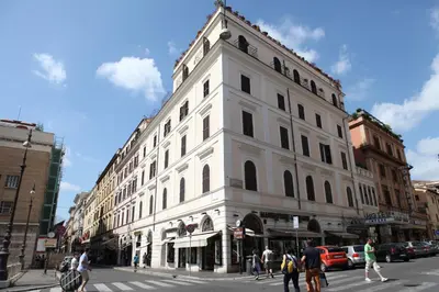 a large white building on a city street with people crossing the street at Hotel Impero in Rome