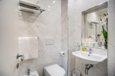 a white bathroom with a sink and a toilet at Hotel San Silvestro in Rome