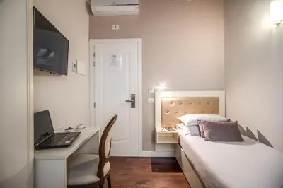 a bedroom with a bed and a desk with a laptop at Hotel San Silvestro in Rome