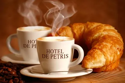 two cups of coffee and a croissant on a table at Hotel De Petris in Rome