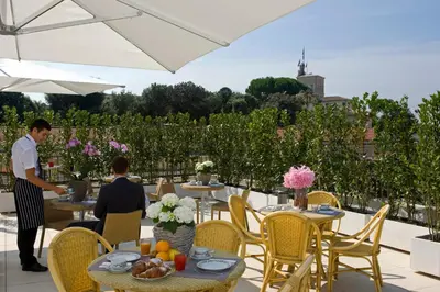 two people sitting at tables on a patio at Hotel De Petris in Rome