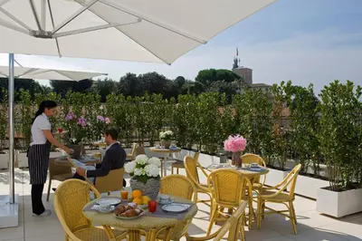 a woman and a man sitting at tables on a patio at Hotel De Petris in Rome