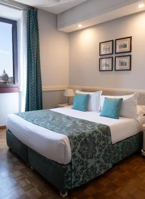 a bedroom with a large bed with blue pillows at Hotel Traiano in Rome