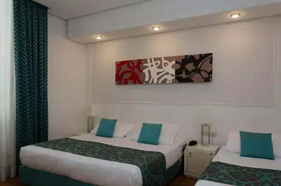 a hotel room with two beds and a painting on the wall at Hotel Traiano in Rome