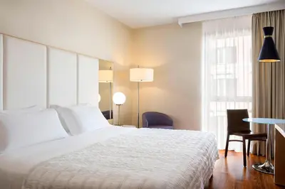 a hotel room with a bed and a desk and a table sidx sidx at Le Meridien Visconti Rome in Rome