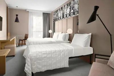 a hotel room with two beds and a chair at Le Meridien Visconti Rome in Rome