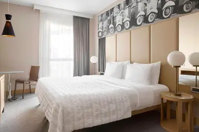 a hotel room with a large white bed and a window at Le Meridien Visconti Rome in Rome