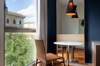 a bedroom with a bed and a blue chair at Le Meridien Visconti Rome in Rome