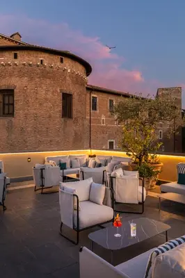 a rooftop patio with white chairs and tables at Room Mate Collection Mia, Rome Colosseum in Rome