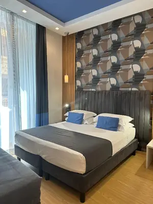 a bedroom with a large bed with blue pillows at Hotel Patria in Rome