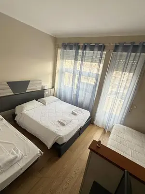 a bedroom with two beds and two windows at Hotel Laura in Rome