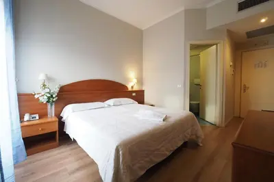 a bedroom with a large white bed with a wooden headboard at Hotel Laura in Rome