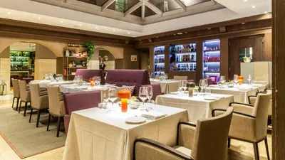 a restaurant with white tables and chairs and wine bottles at Hotel Indigo Rome - St. George by IHG in Rome