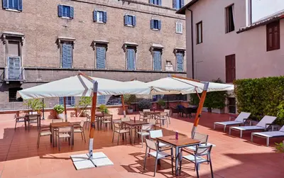 a patio with tables and chairs and white umbrellas at Hotel Indigo Rome - St. George by IHG in Rome