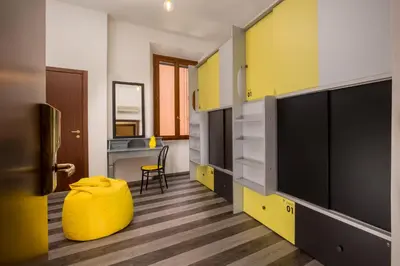 a room with yellow walls and a yellow ottoman at Free Hostels Roma in Rome