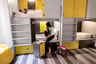 a woman sitting on a desk in a room with bunk beds at Free Hostels Roma in Rome