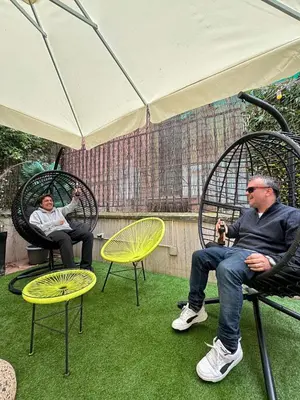 two men sitting in chairs under an umbrella at Free Hostels Roma in Rome