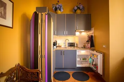 a small kitchen with a refrigerator and an open door at Suite Casa Pariolina in Rome