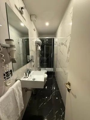 a white bathroom with a sink and a mirror at Relais Fontana Di Trevi Hotel in Rome