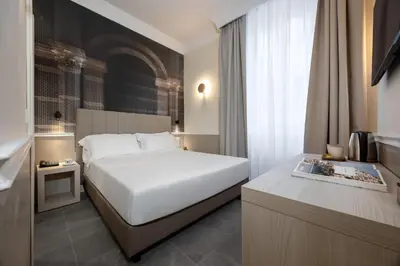 a hotel room with a white bed and a desk at Hotel Astoria Garden in Rome