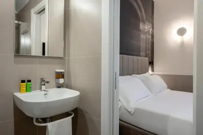 a white bedroom with a bed and a tv at Hotel Astoria Garden in Rome