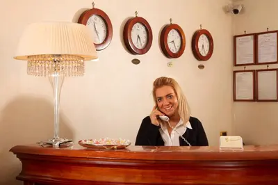 a woman sitting at a desk talking on a cell phone at Hotel Serena srl in Rome