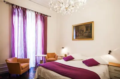 a bedroom with a bed and two chairs and a chandelier at La Dolce Vita Roma in Rome