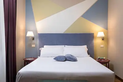 a bedroom with a bed with two blue pillows on it at Boutique Hotel Galatea in Rome