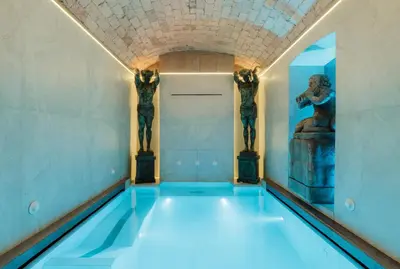 a swimming pool in a museum with two statues at Romanico Palace Luxury Hotel & SPA in Rome