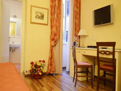 a room with a desk and a table with a vase of flowers at Residenza Domiziano in Rome