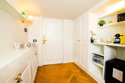 a kitchen with white cabinets and a hard wood floor at Splendor Suite Rome - Suites & Apartments in Rome
