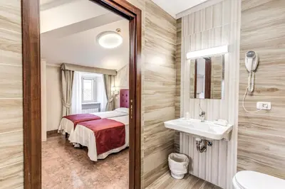 a bathroom with a bed and a sink and a mirror at Hotel Milo in Rome