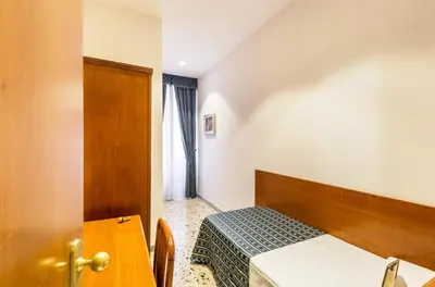 a small room with a bed and a table at Hotel Tempio Di Pallade in Rome