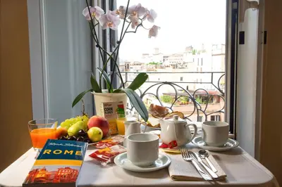 a table with coffee cups and fruit and a vase with flowers at Tourist House B&B in Rome