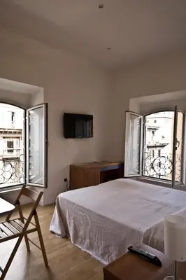 a bedroom with a bed and two large windows at Tourist House B&B in Rome