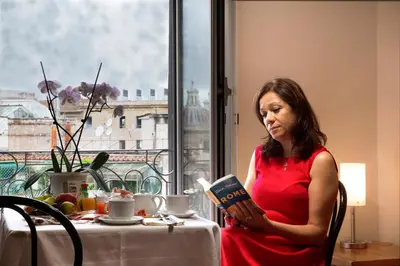 a woman sitting at a table reading a book at Tourist House B&B in Rome