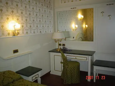 a room with a bed and a desk and a mirror at Hotel Dina in Rome