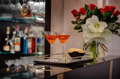 two martini glasses on a bar with a vase of flowers at Dharma Boutique Hotel & SPA in Rome