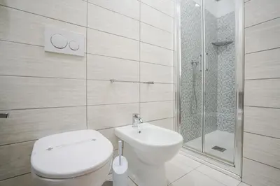 a white bathroom with a toilet and a shower at Hotel St. Moritz in Rome