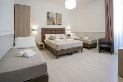 a hotel room with two beds and a chair at Hotel St. Moritz in Rome