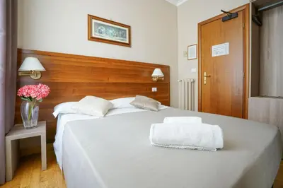 a bedroom with a white bed with a vase of flowers at Hotel St. Moritz in Rome