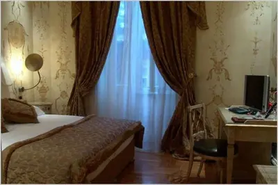 a bedroom with a bed and a desk and a window at San Anselmo in Rome