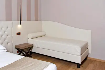 a white bedroom with two beds and a table at Hotel Arcangelo in Rome