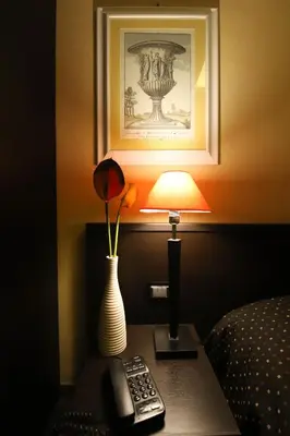 a lamp on a table with a remote control and a vase at Hotel Latinum in Rome