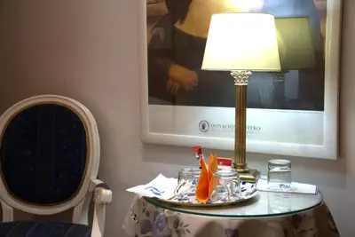 a table with a lamp on a table with a chair at Hotel Locanda Cairoli in Rome