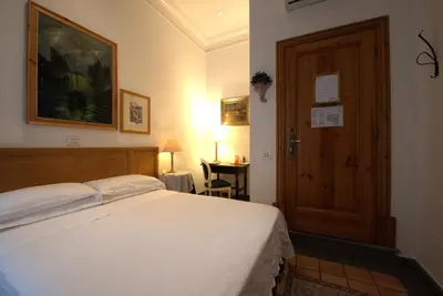 a bedroom with a bed and a wooden door at Hotel Locanda Cairoli in Rome
